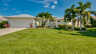 Elegante Villa Donatella in Cape Coral mit gepflegtem Vorgarten, Palmen und tropischer Bepflanzung. Einladender Eingangsbereich mit Doppeltüren und mediterranem Charme. - Traum-Urlaub-Florida