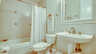 Modernes Badezimmer mit Badewanne, Duschvorhang und eleganter Keramik-Ausstattung. - Traum-Urlaub-Florida