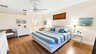 Hauptschlafzimmer mit gestreiftem Kingsize-Bett, Korbstuhl und Durchgang zum Bad - Traum-Urlaub-Florida