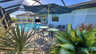 Gemütliche Sitzecke am Pool mit Sonnenschirm und tropischer Bepflanzung. - Traum-Urlaub-Florida