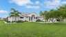 Villa Kamala in Cape Coral mit weißer Fassade, Palmen und gepflegtem Vorgarten. - Traum-Urlaub-Florida