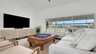 Modernes Wohnzimmer mit Sofalandschaft, TV und großer Fensterfront zur Poolterrasse. - Traum-Urlaub-Florida