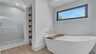 Modernes Badezimmer mit freistehender Badewanne, ebenerdiger Dusche und großem Fenster mit Tageslicht. - Traum-Urlaub-Florida