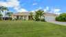 Außenansicht der Villa Nevena in Cape Coral mit Palmen und gepflegtem Vorgarten. - Traum-Urlaub-Florida
