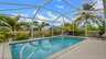 Pool mit Sonnenterrasse, Screen und Blick auf Palmen und den Wasserkanal. - Traum-Urlaub-Florida