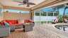 Gemütliche Sitzecke mit rotem Outdoor-Sofa und Feuertisch unter dem geschützten Terrassenbereich, direkt am Poolbereich mit Screen-Konstruktion aus Aluminium und Fliegengitter. - Traum-Urlaub-Florida