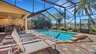 Sonnenliegen am Pool mit Screen, überdachter Essbereich mit Steinkamin im Hintergrund - Traum-Urlaub-Florida