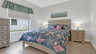 Gemütliches Schlafzimmer mit maritimem Bettwäsche-Design, zwei Nachttischen und Fenster mit Blick in den Garten. - Traum-Urlaub-Florida