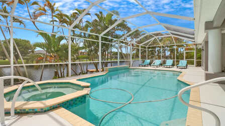 Überdachter Poolbereich mit Spa, Sonnenliegen und Blick auf den Kanal – umgeben von tropischer Vegetation - Traum Urlaub Florida 