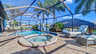 Poolbereich mit integriertem Whirlpool, Sonnenliegen und tropischer Bepflanzung am Kanal. - Traum-Urlaub-Florida