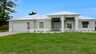 Moderne, einstöckige Villa Cupido in Cape Coral mit weißer Fassade, gepflegtem Rasen und überdachtem Eingangsbereich. - Traum-Urlaub-Florida