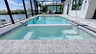 Blick vom Whirlpool auf den langgestreckten Pool mit moderner Travertin-Umrandung und Screen. - Traum-Urlaub-Florida