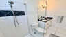 Modernes Bad mit bodengleicher Dusche, Glaswand, Waschtisch mit Granit und heller Beleuchtung. - Traum-Urlaub-Florida