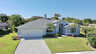Frontansicht der Villa Amagalla in Cape Coral mit Einfahrt, gepflegtem Garten und Palmen unter blauem Himmel. - Traum-Urlaub-Florida
