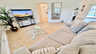Helles Wohnzimmer mit großem Sofa, Glastisch, TV und offenem Grundriss mit Blick Richtung Poolbereich. - Traum-Urlaub-Florida