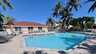 Großer Poolbereich mit Sonnenliegen, Palmen und angrenzendem Gemeinschaftsgebäude - Traum-Urlaub-Florida