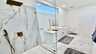 Luxuriöses Badezimmer mit bodengleicher Regendusche, modernem Waschtisch und elegantem Marmordesign. - Traum-Urlaub-Florida