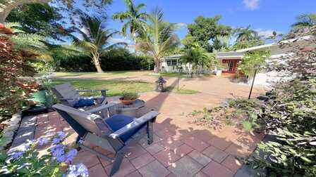 Gemütlicher Sitzbereich im tropischen Vorgarten mit Palmen, blühenden Pflanzen und Blick auf die Ferienvilla in Fort Myers. - Traum Urlaub Florida 