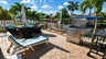 Kanalterrasse mit Korb-Loungesesseln, gestreifter Sonnenliege, Gasgrill und Palmen - Traum-Urlaub-Florida
