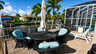 Rundes Korb-Essset mit Sonnenschirm auf Kanalterrasse neben Gasgrill und Poolkäfig - Traum-Urlaub-Florida