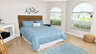 Schlafzimmer mit Queensize-Bett, drei Rundbogenfenstern, blauem Teppich und Flechtpouf - Traum-Urlaub-Florida