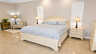 Schlafzimmer mit Kingsize-Bett, zwei Nachttischen, Polsterbank in der Ecke und Schrank mit Palmenmotiv - Traum-Urlaub-Florida