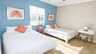 Schlafzimmer mit Queen- und Einzelbett, blauer Akzentwand, Korallenbildern und Schminktisch - Traum-Urlaub-Florida
