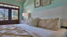 Schlafzimmer mit gesteppter Bettdecke, Wandbildern und Glastüren mit Jalousien zu Palmen - Traum-Urlaub-Florida