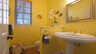 Gelbes Badezimmer mit Säulenwaschbecken, goldenen Armaturen, Fenster und Krebswanddeko - Traum-Urlaub-Florida