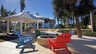 Terrasse mit Feuerstelle, bunten Adirondack Stühlen, weißem Pavillon und Palmen - Traum-Urlaub-Florida