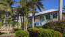 Zweistöckige Hausfassade mit grünen Fensterläden, Palmen und blühenden Sträuchern - Traum-Urlaub-Florida