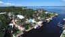Luftaufnahme von Kanalhäusern mit weißen Dächern, geschwungenem Pool, Stegen und breitem Fluss - Traum-Urlaub-Florida