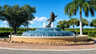 Runder mehrstufiger Springbrunnen mit springender Fischskulptur und Palmen im Hintergrund - Traum-Urlaub-Florida