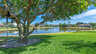 Grüne Gartenlandschaft mit schattigem Baum, Seeschaukel und ruhigem See, umgeben von gepflegten Häusern. - Traum-Urlaub-Florida